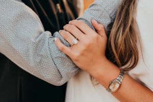 Close-up of hands with engagement ring and bracelet showing affectionate gesture.