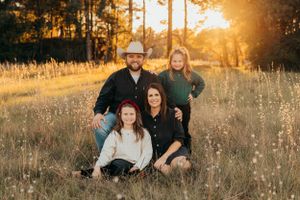 Group portrait in a sunlit meadow with pine trees in background.