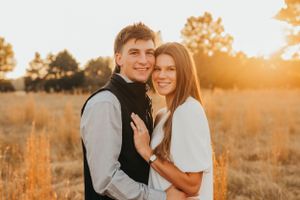 Romantic couple poses in a sun-drenched field during golden hour with natural autumn scenery.