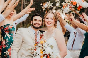 Wedding couple celebrating under shower of flower petals during outdoor ceremony.