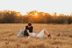Couple relaxing in a golden grass field during sunset.