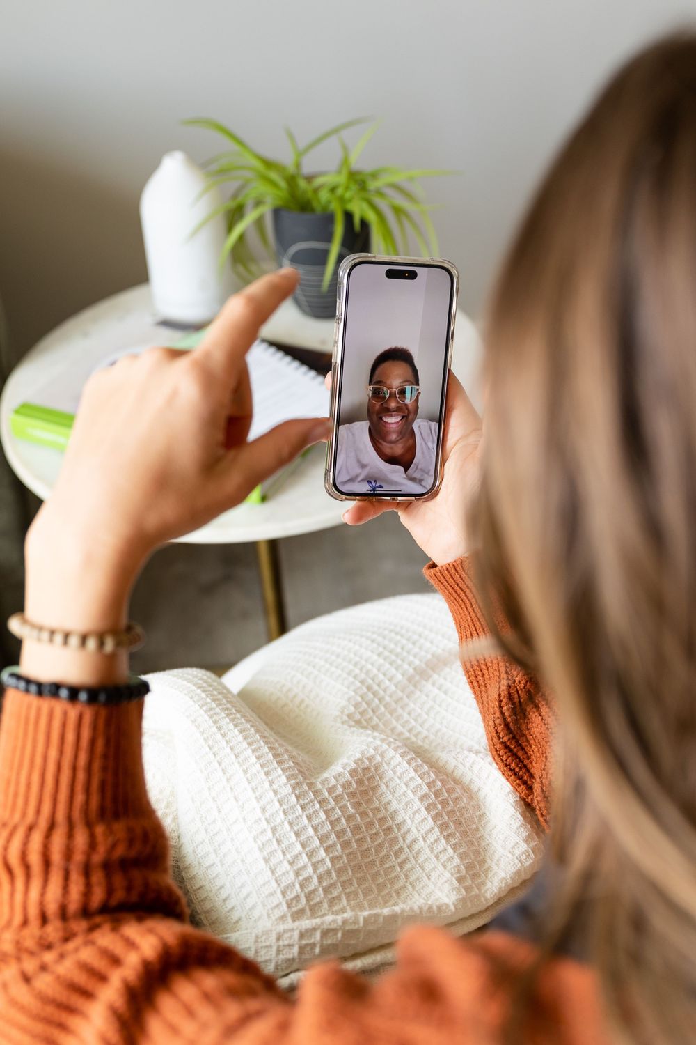 a woman talking to someone on facetime on her phone. focus is the camera with the back of her head in the foreground