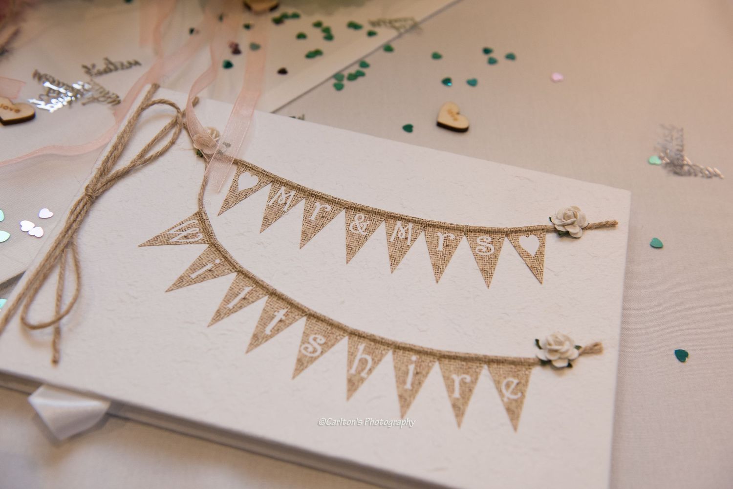 Wedding stationery details with rustic burlap bunting banners and elegant calligraphy on white paper.