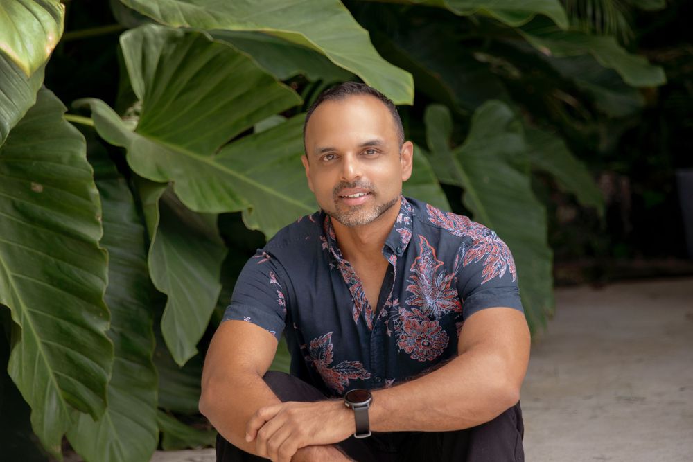 Tropical portrait with large green leaves and floral shirt.