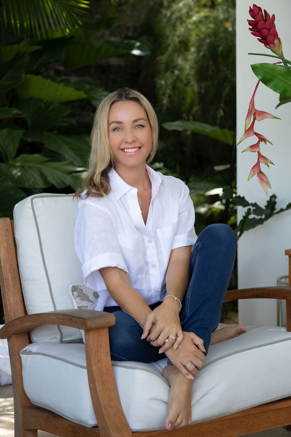 Casual outdoor tropical setting with white chair and vibrant red heliconia flower.