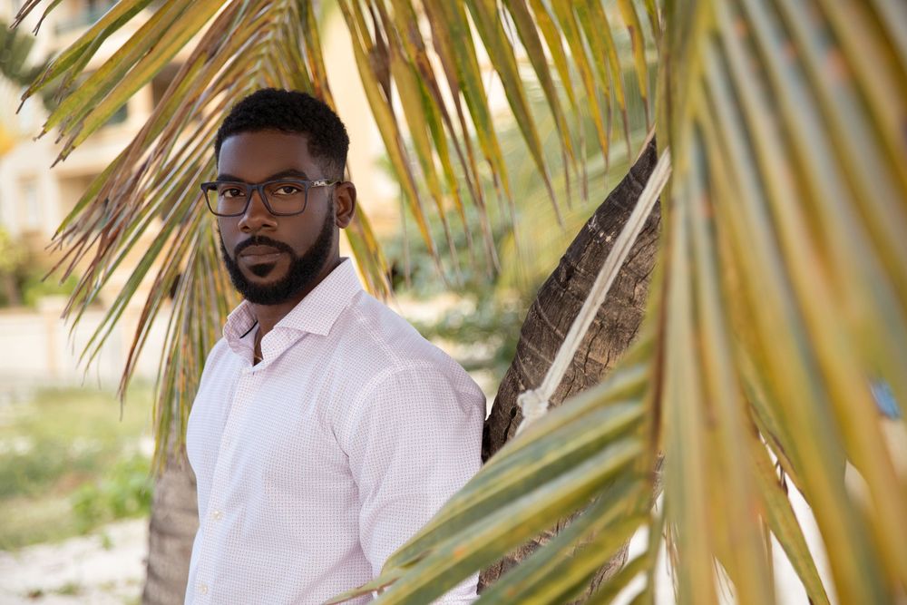 Portrait of person in white shirt under tropical palm fronds.