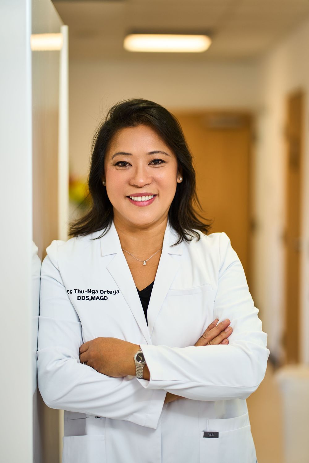 Healthcare professional in white coat standing confidently in medical office hallway.