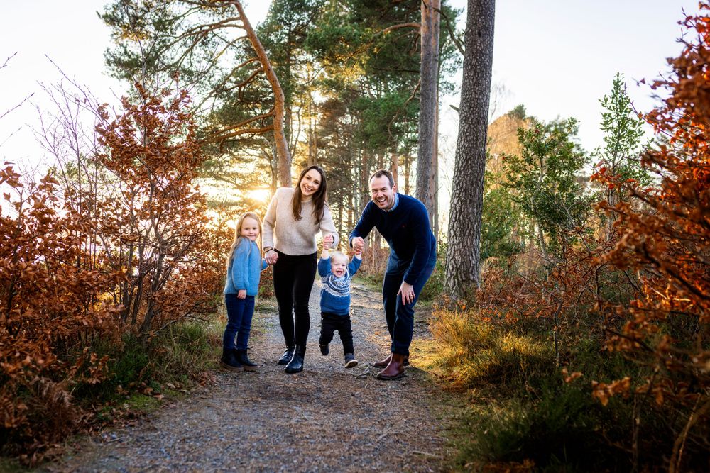 Family walking together on forest trail during autumn sunset.