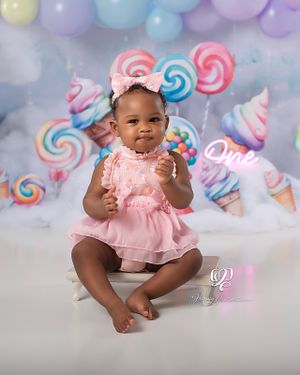 One year old baby girl wearing pink tulle dress for Cake Smash Session with pastel balloon arch and candy props; best professional photos