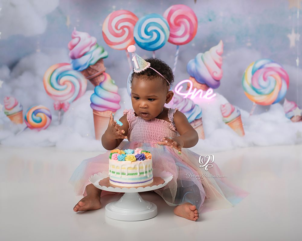 Birthday baby eating birthday cake for first birthday photoshoot; pastel theme with candy, balloons, clouds; best photographer Lexington, SC