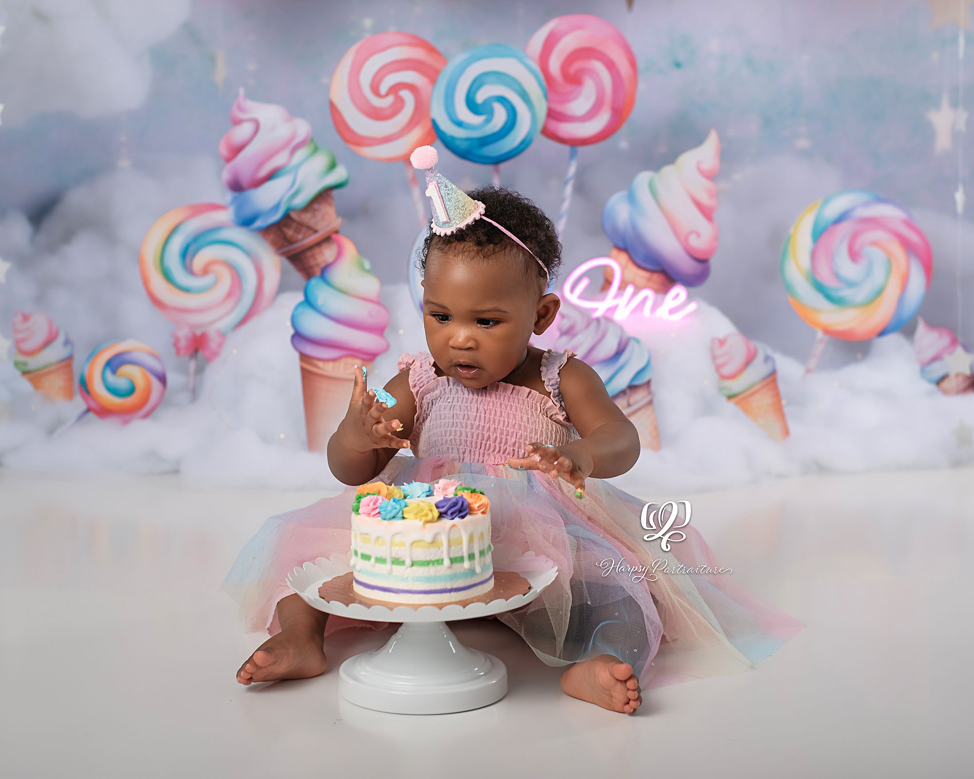 Birthday baby eating birthday cake for first birthday photoshoot; pastel theme with candy, balloons, clouds; best photographer Lexington, SC