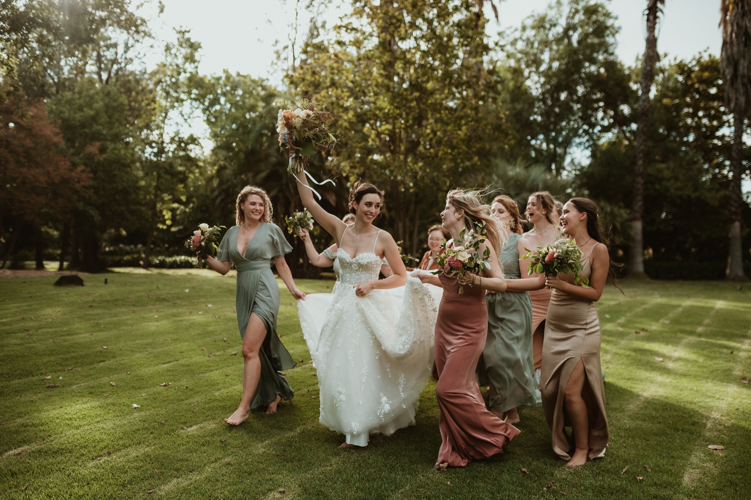 A celebration on a sunlit lawn with people dancing together in colorful dresses.