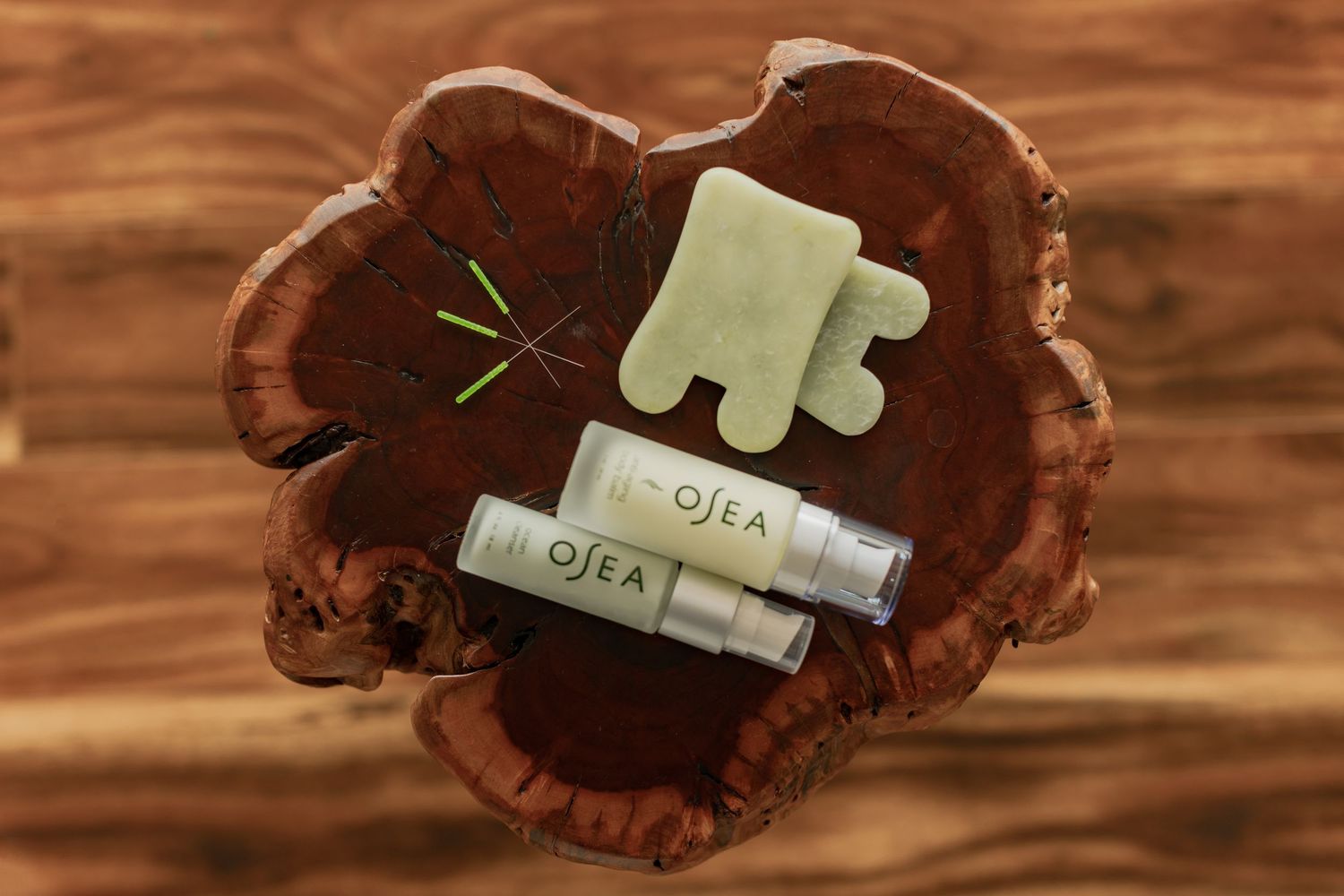 OSEA skincare products with jade gua sha tool displayed on rustic wooden surface.