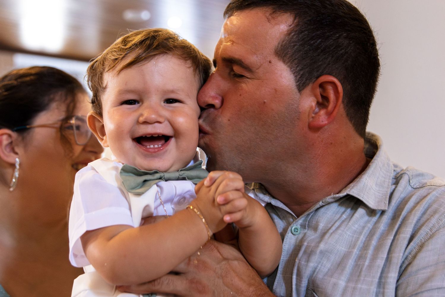 Joyful moments shared between adults and baby in bright indoor setting.