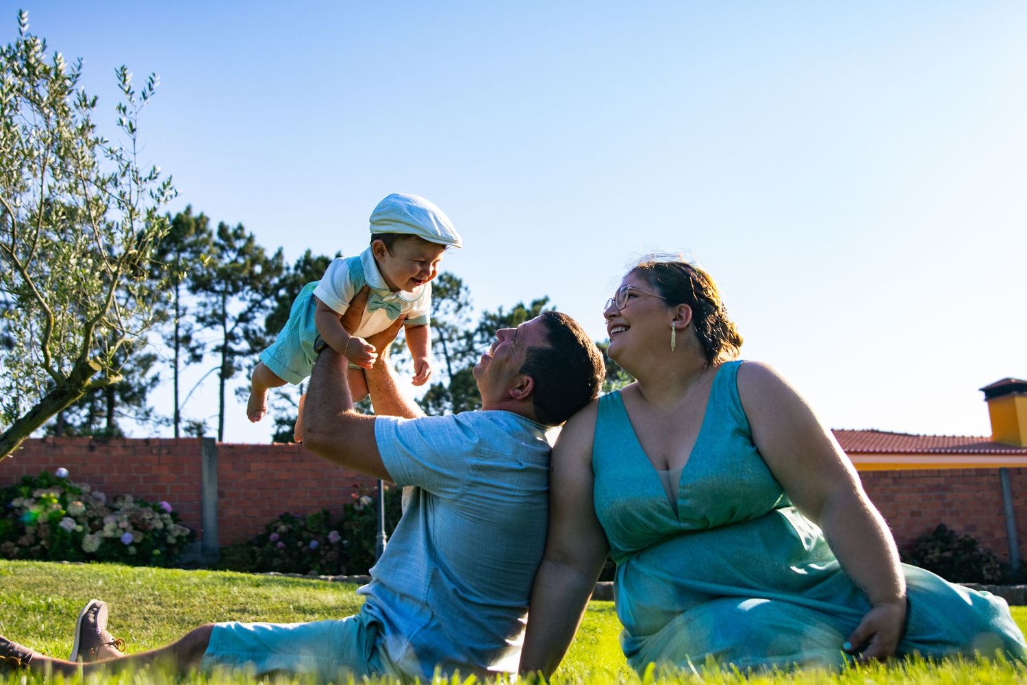 Family members lying on grass enjoying a sunny day outdoors.