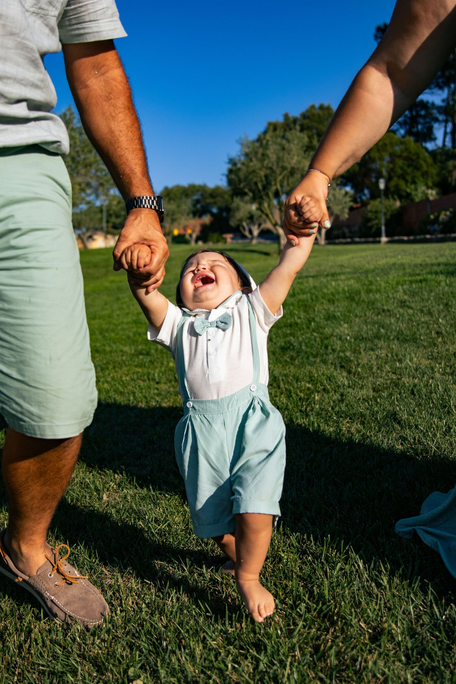 Close-up shots of small feet walking on grass while holding hands.