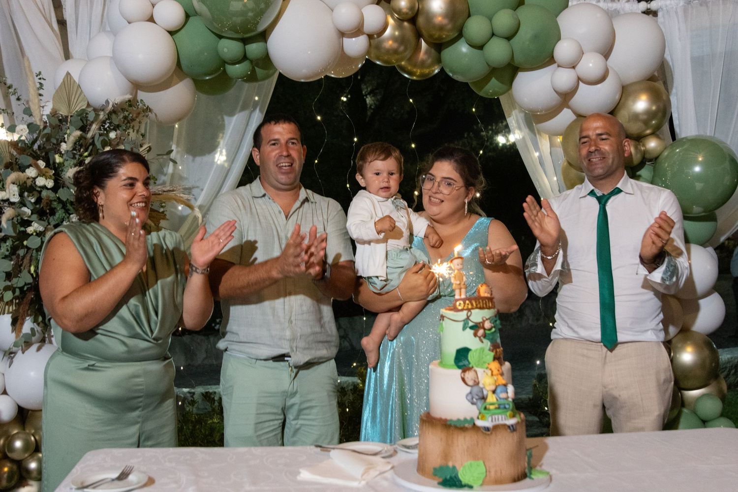 Celebration scene with green and white balloons decorating an indoor space.