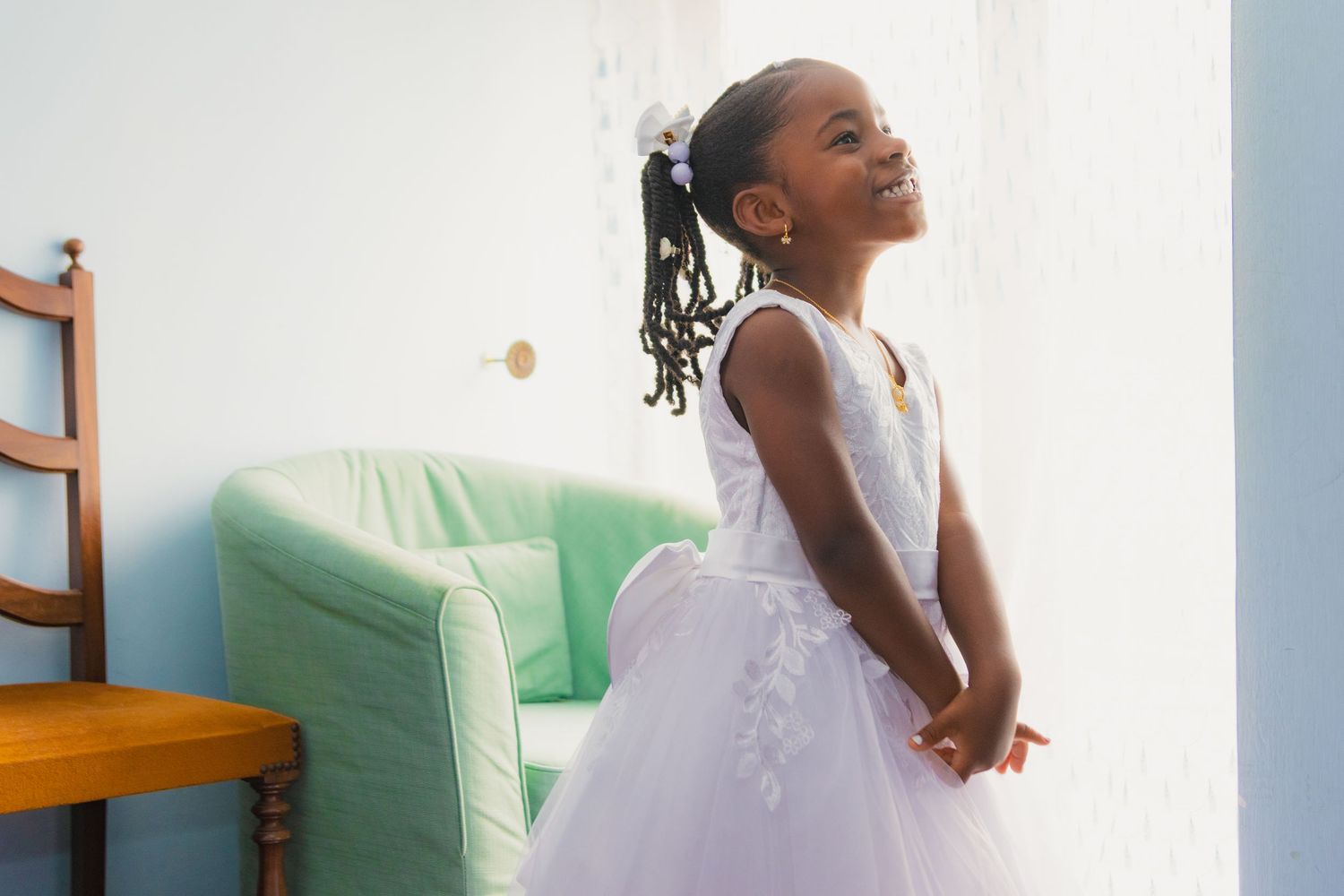 Person in white dress sits thoughtfully on green couch while looking up in contemplative pose.