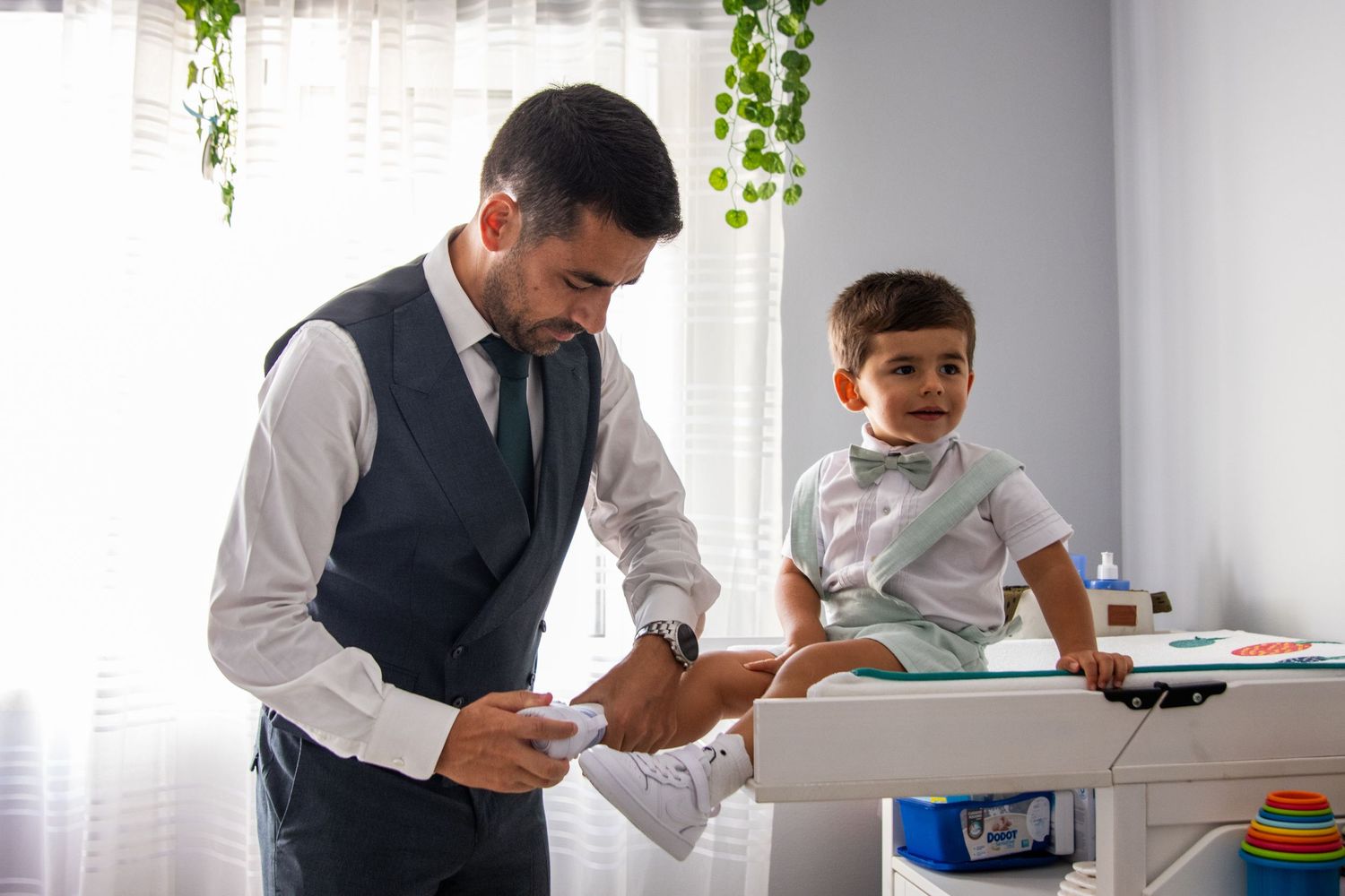 Father and son in formal attire preparing for special event at home.