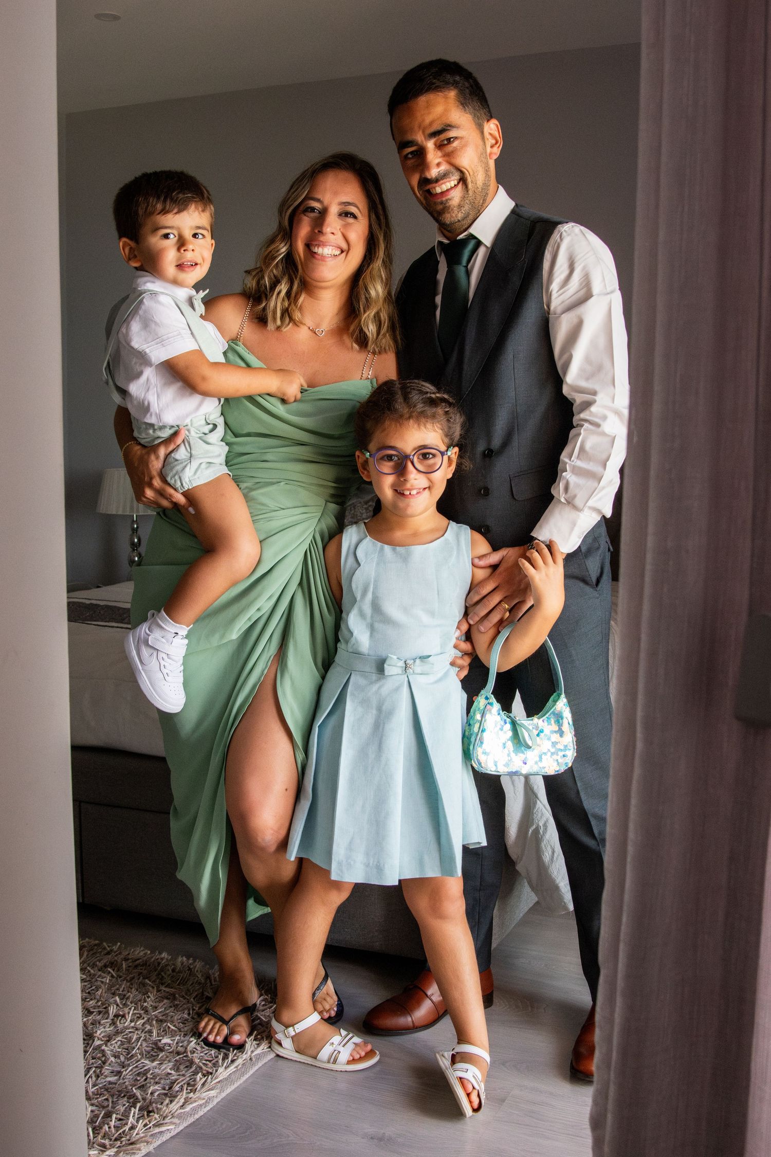 Family in formal attire poses together in doorway before special event.