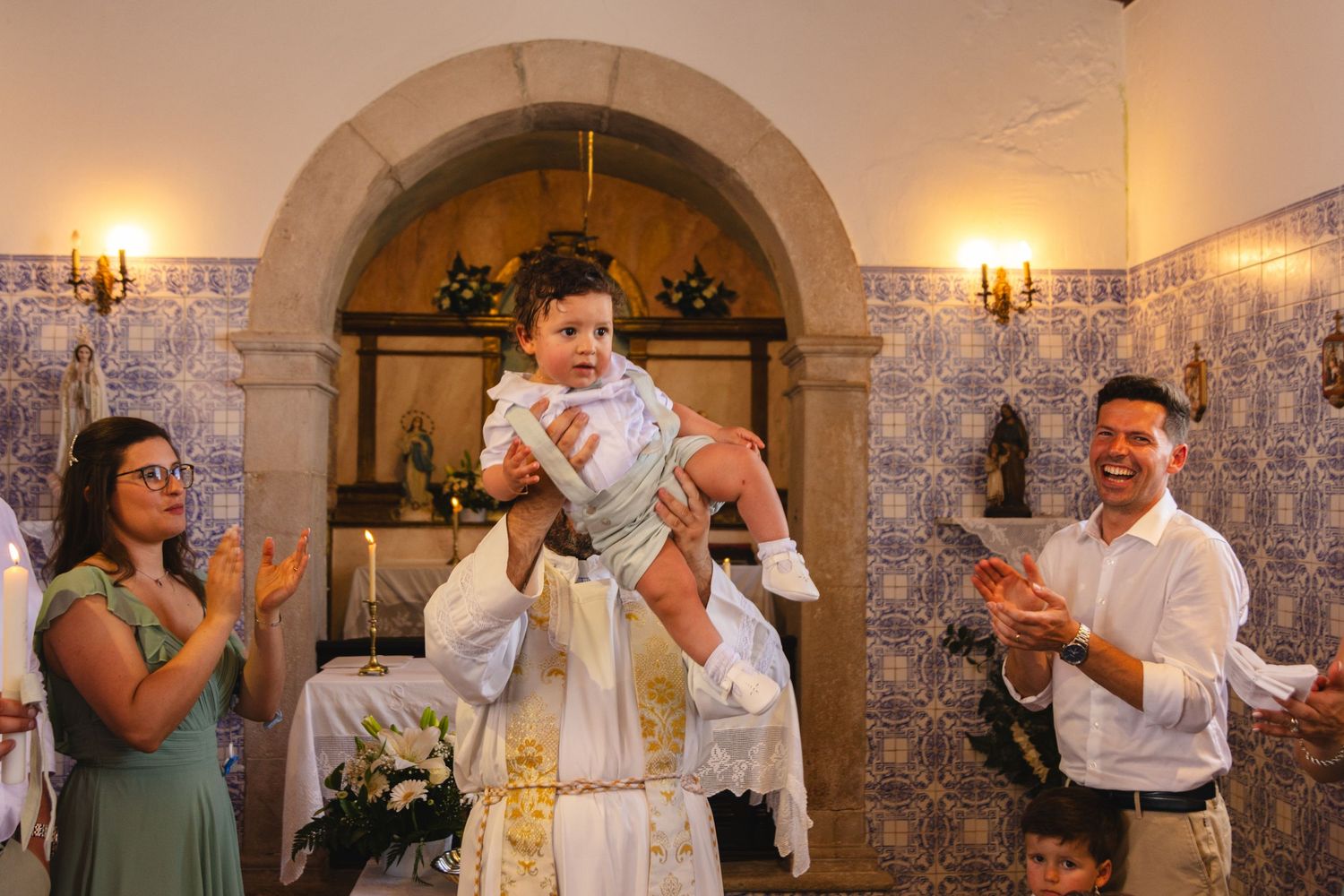 Baptism celebration in ornate church with decorative arches and candles.