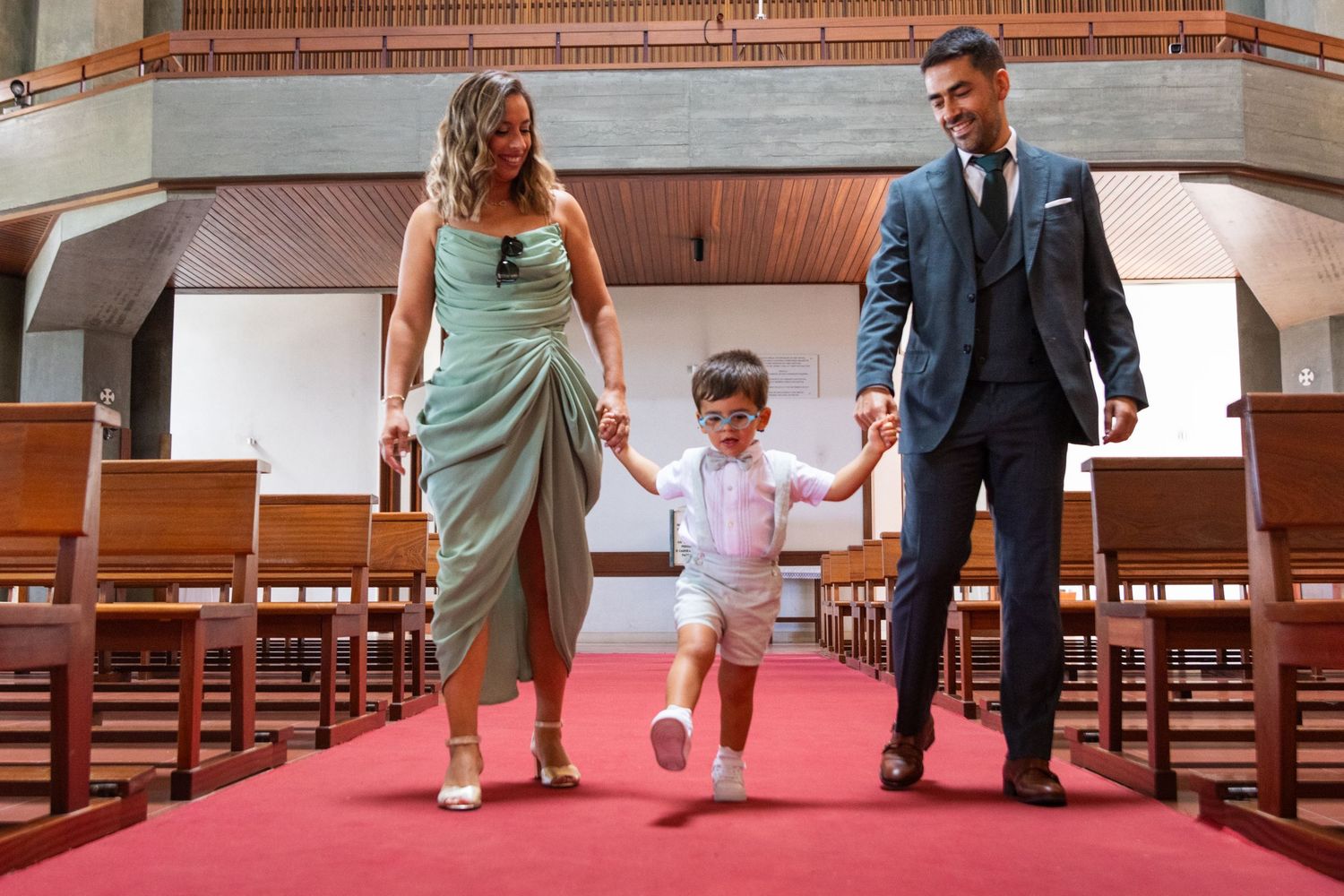 Family walking hand in hand down red-carpeted church aisle.