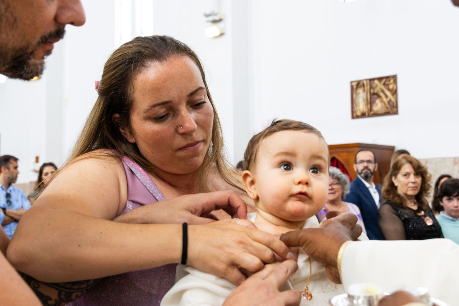 A tender moment during a religious ceremony with a baby in white baptismal attire.