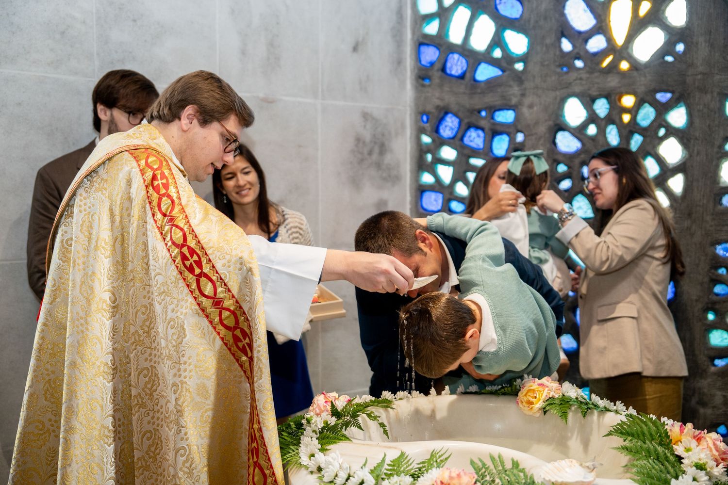 Sacred ceremony being performed in front of ornate stained glass windows.