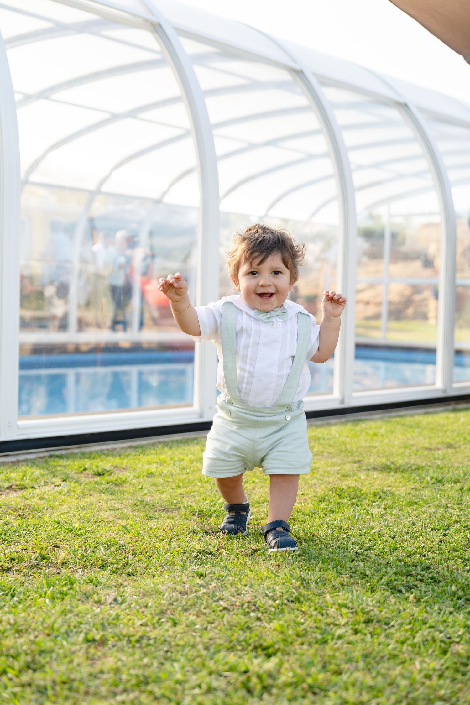 A sequence of joyful moments on grass with a covered structure in the background.