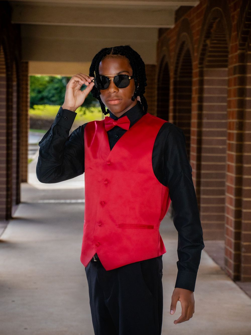 Five sequential photos show someone in a red vest and black shirt posing in a brick hallway while wearing sunglasses.