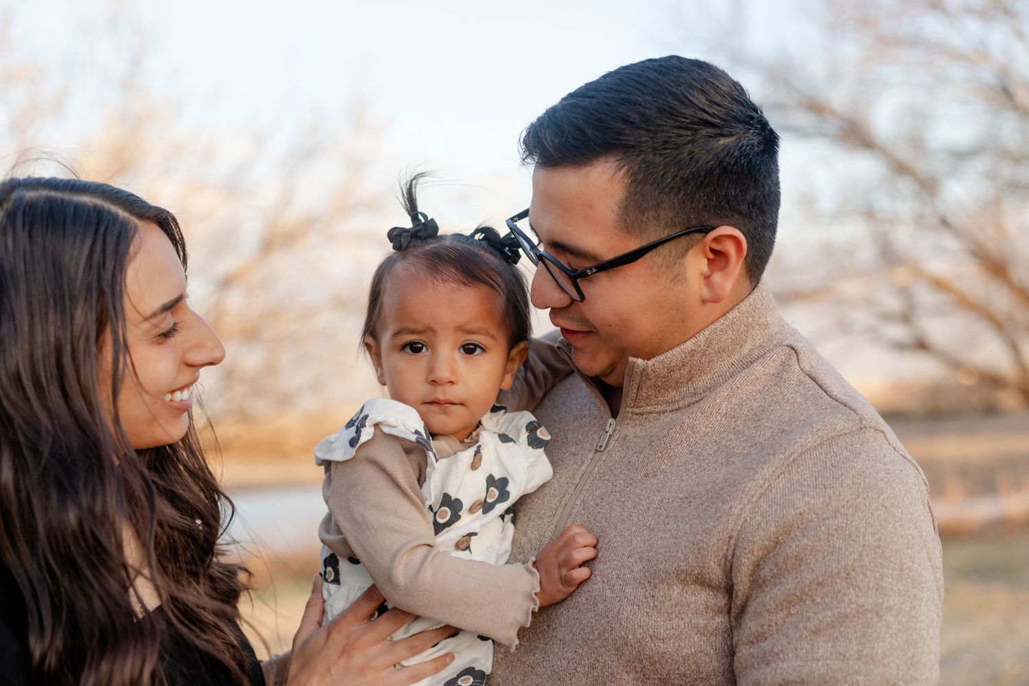 A tender family moment captured outdoors with warm golden lighting.