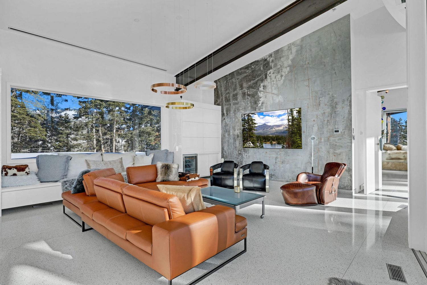 Modern living room with leather sofa, stone accent wall, large windows, and polished floors. Captured by Slate Media (best in UT)