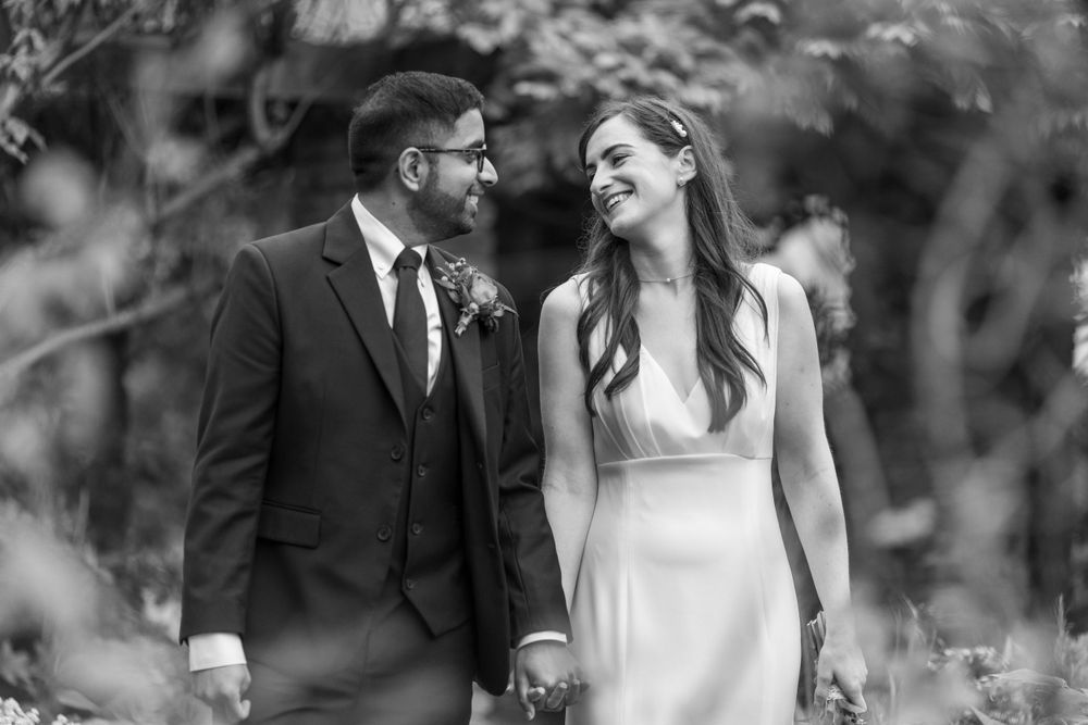 A black and white candid moment of newlyweds sharing a joyful laugh together.