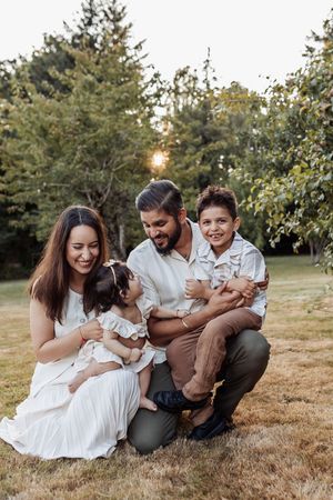Family laughing together during sunset photoshoot in garden setting.