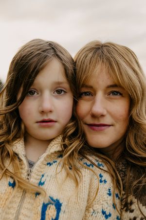 Close-up portrait of two people with similar honey-blonde hair wearing matching sweaters.