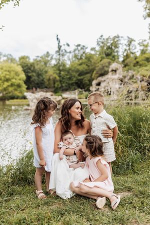 Family gathering by lakeside with children and baby in white summer outfits.