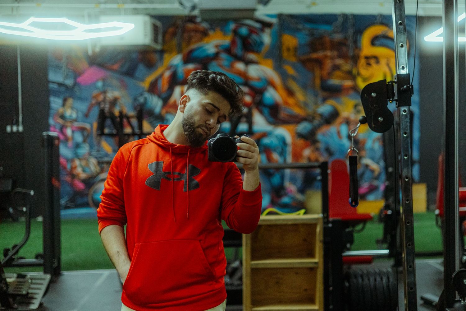 Male model in red hoodie looking off-camera with serious expression
