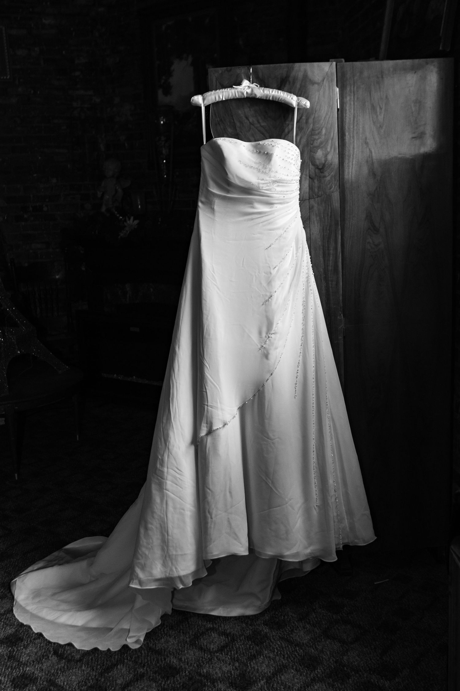 A strapless white wedding dress is photographed on its own using window light at Yesterday's Plaza in Klamath Falls, OR.