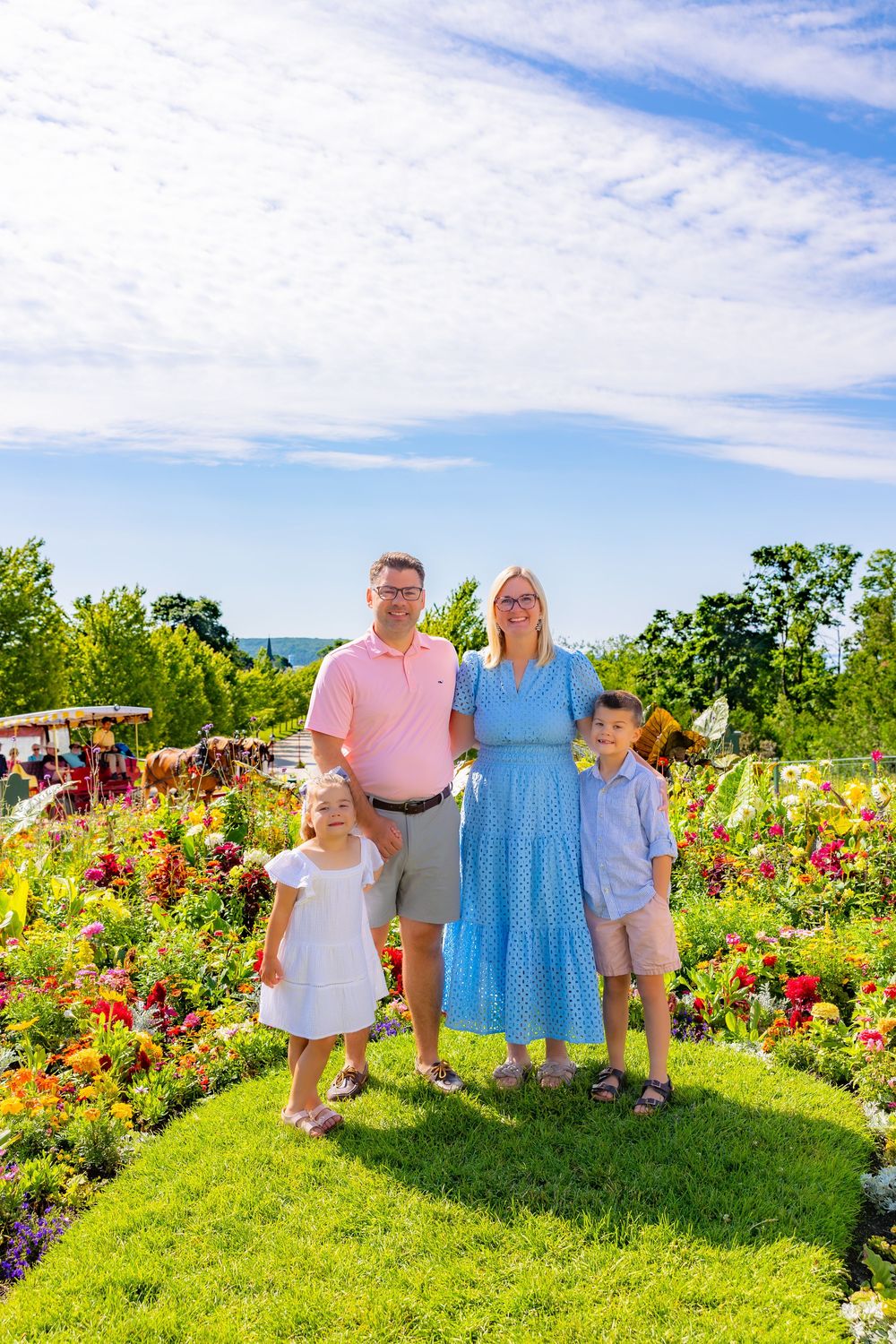 A family poses together in a vibrant garden filled with colorful flowers on a sunny summer day.