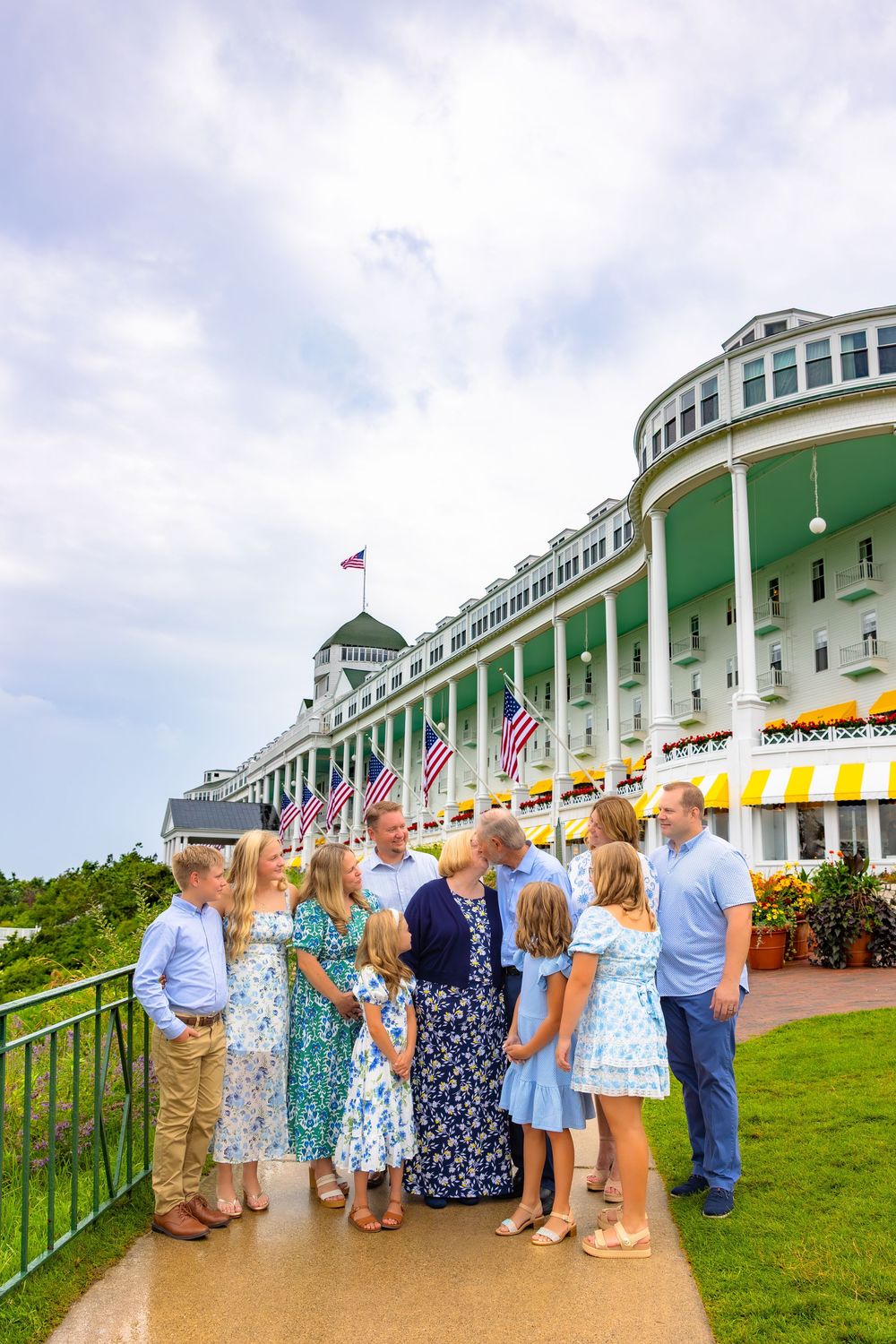 A group of guests gather on the Grand Hotel porch overlooking Mackinac Island on a cloudy summer day.