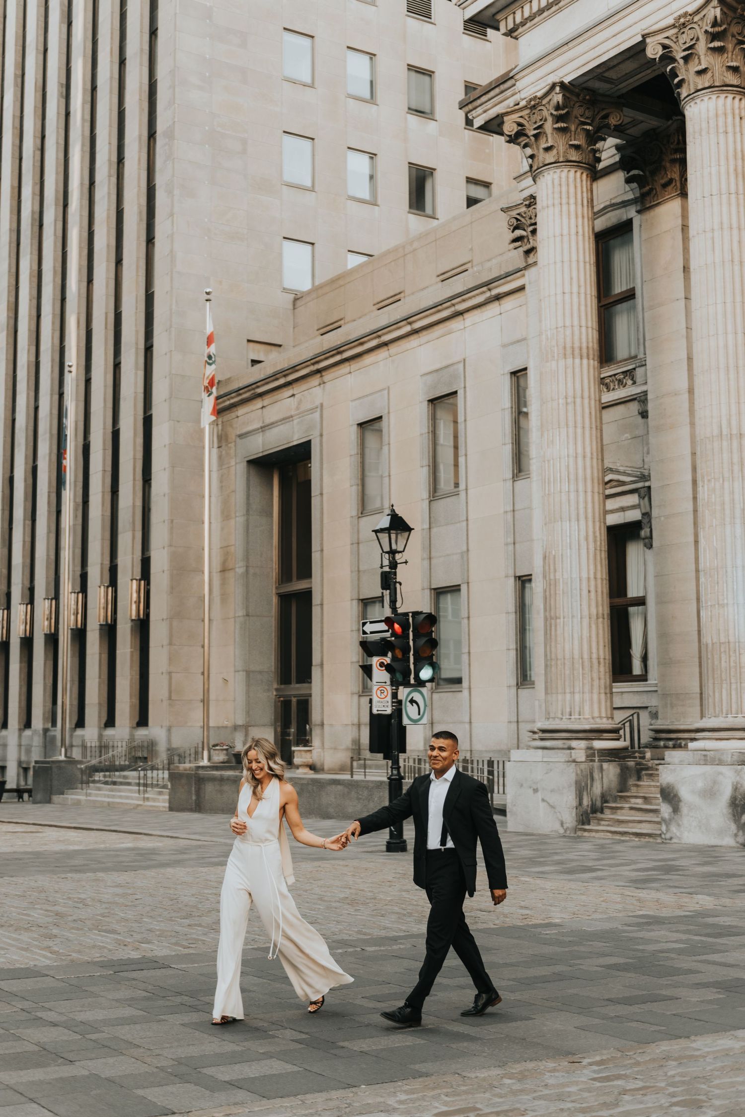 A wedding couple dances and twirls through an elegant courtyard with neoclassical columns and architecture.