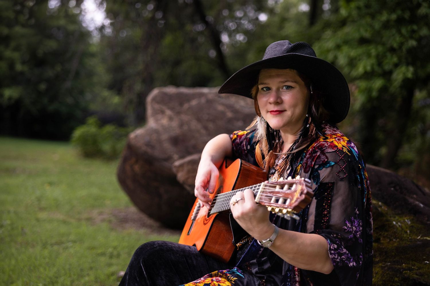 A woman plays her guitar in the park.