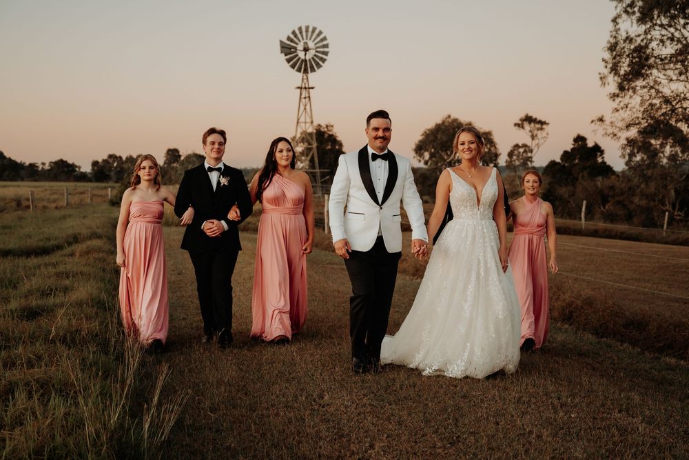 Bridal party in pink dresses poses together at hedlow retreat wedding venue at sunset.