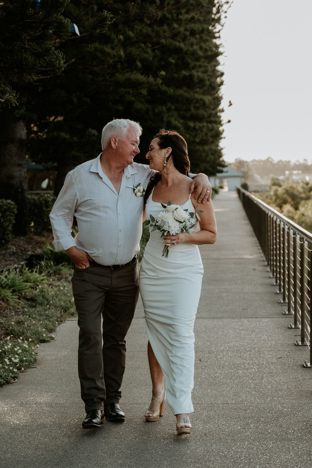 Couple takes romantic stroll along gladstone marina elevated pathway with scenic city views.
