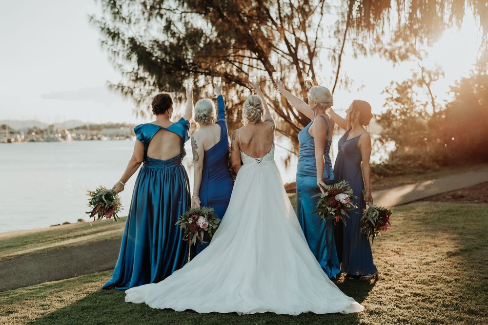 Wedding party in blue dresses posing outdoors at sunset at gladstone spinnaker park.