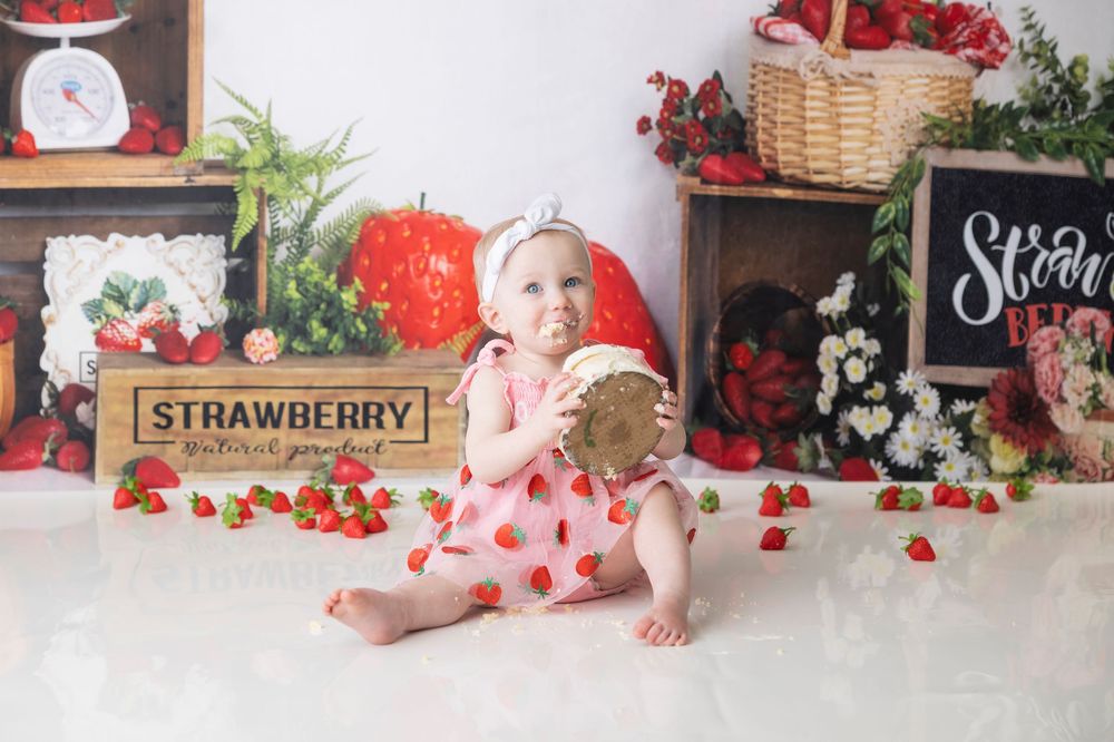 Strawberry themed photo setup with vintage scale, wooden crates, baskets and heart decorations in red and white tones.