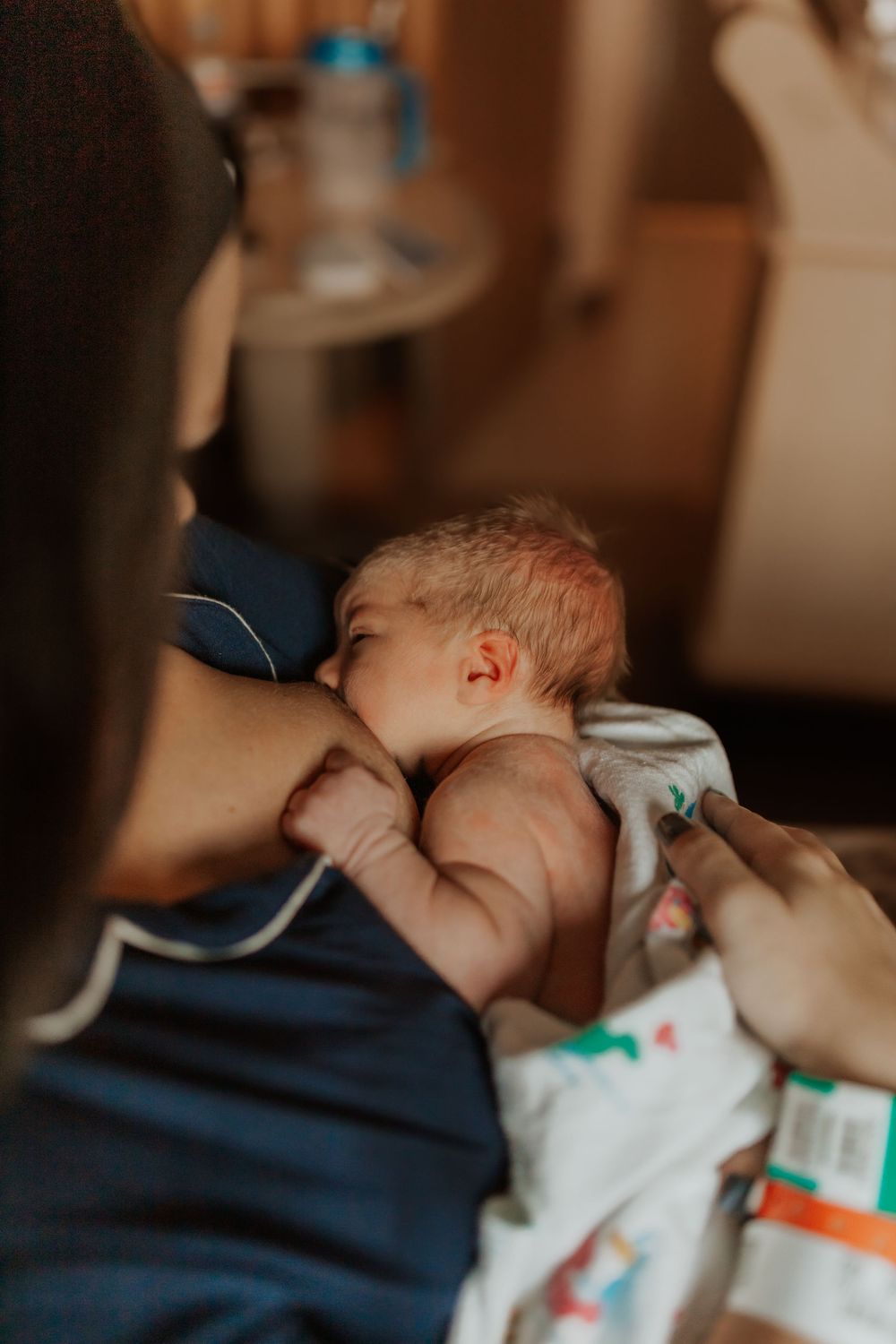 Intimate moment of nursing newborn baby in hospital room.