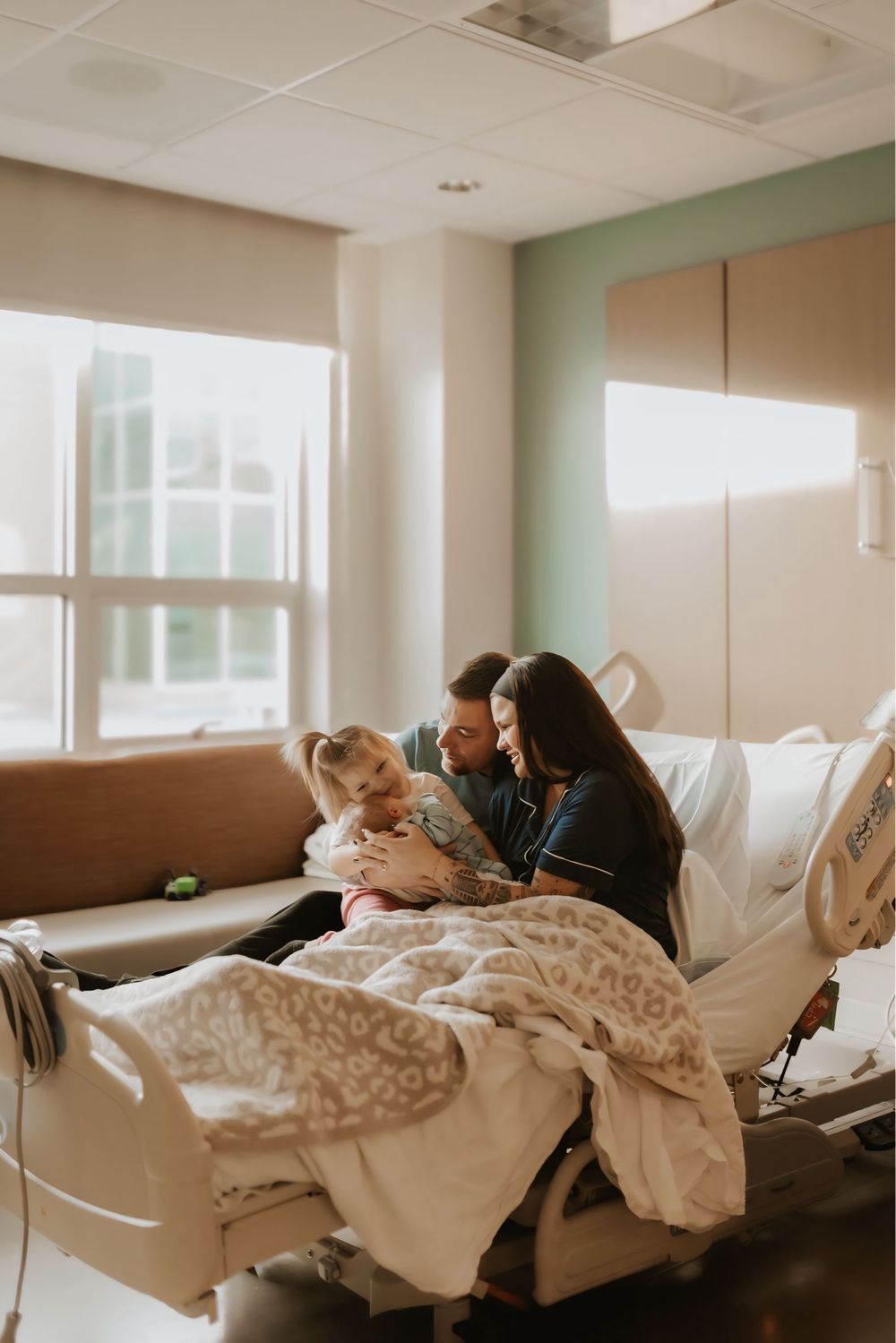 Hospital room scene with family gathered around bed during postpartum stay.