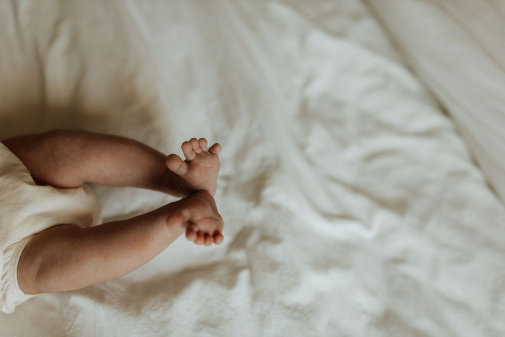 Close-up photos of baby feet on white sheets arranged in a horizontal collage.