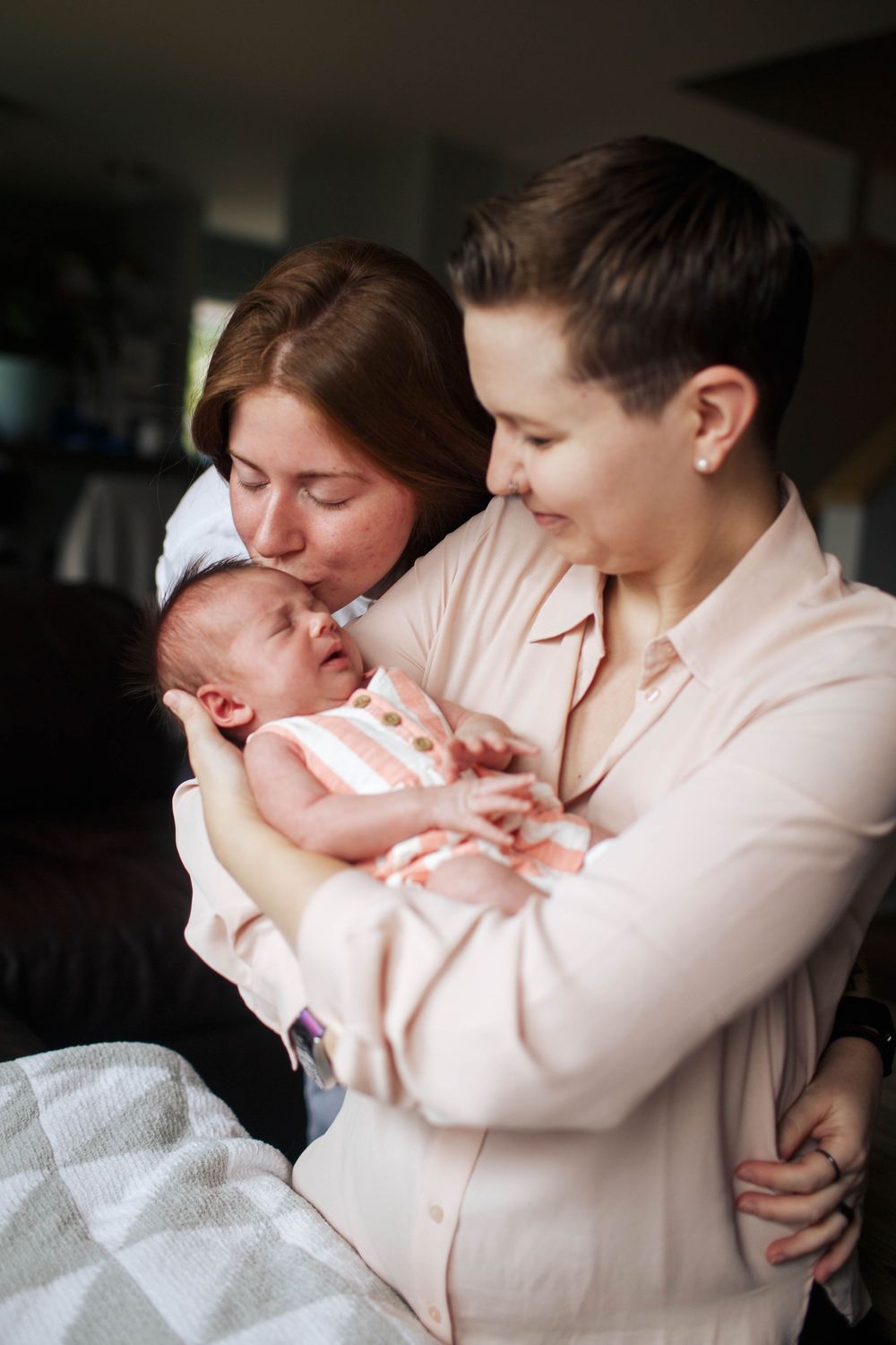 Marysville newborn photographer: Two new mothers hold their newborn baby girl at an in-home newborn photo session